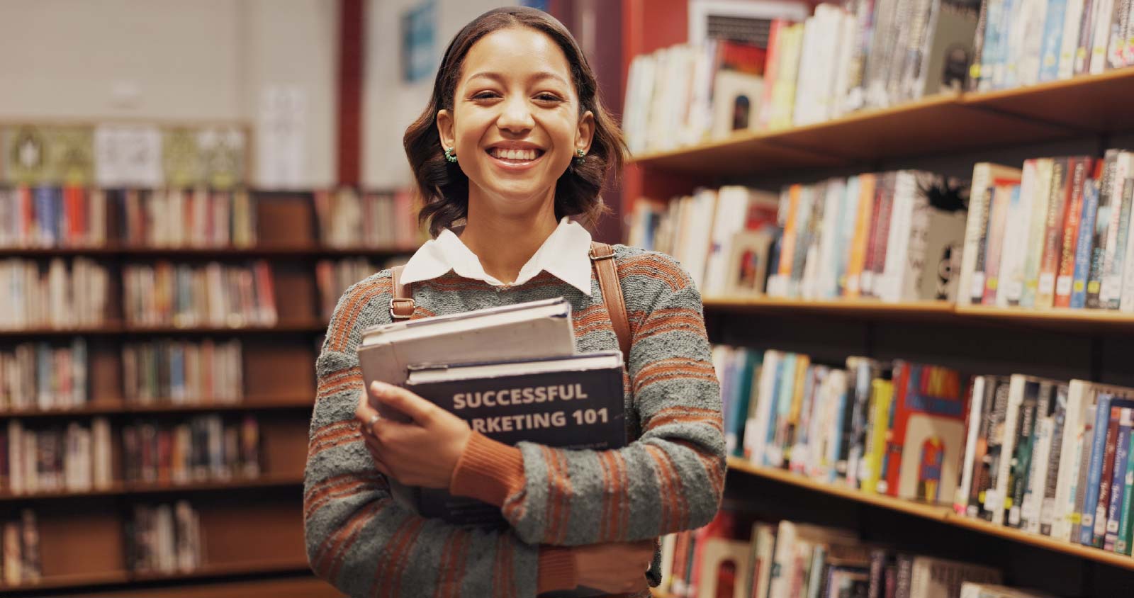 Young woman in a library with a book on marketing